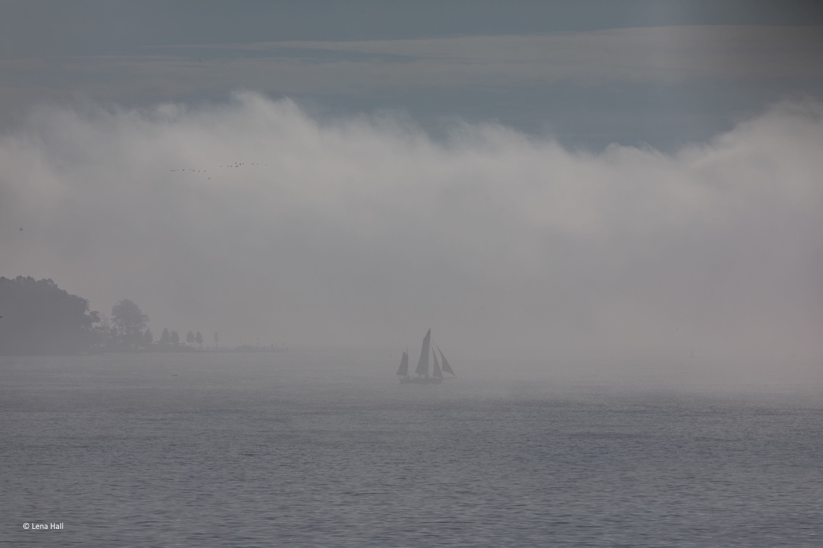 neblige See mit Segelboot, dass im Nebel verschwindet als Sinnbild für Weite und Übergang und Loslassen im Herbst durch Coaching für Frauen in Führung